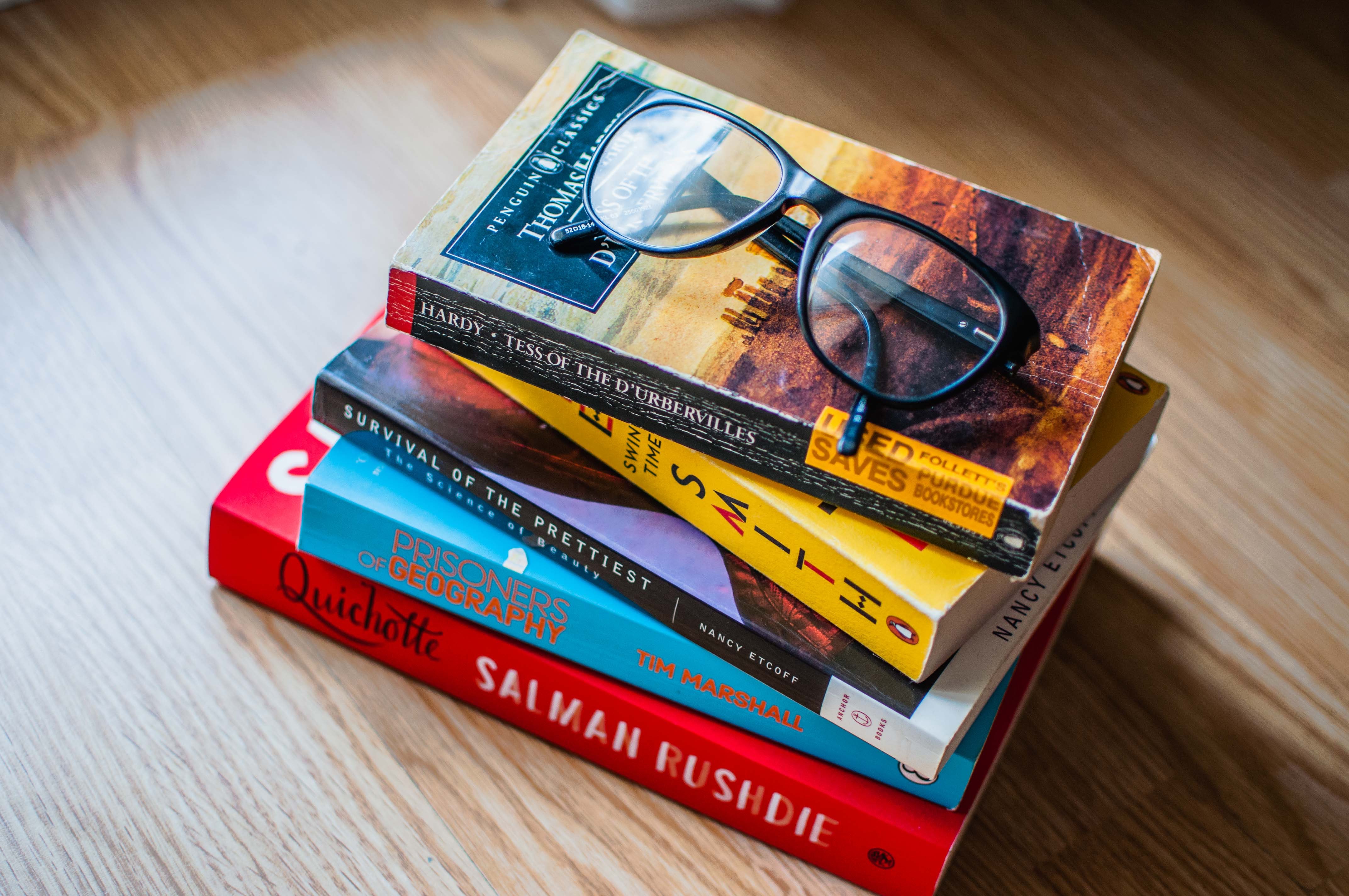 stack of books from around the world with reading glasses on top from localbini biniblog local travel experiences quarantine home 